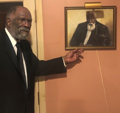 Fred D. Perkins in his home next to portrait of a personal hero, Frederick Douglass.